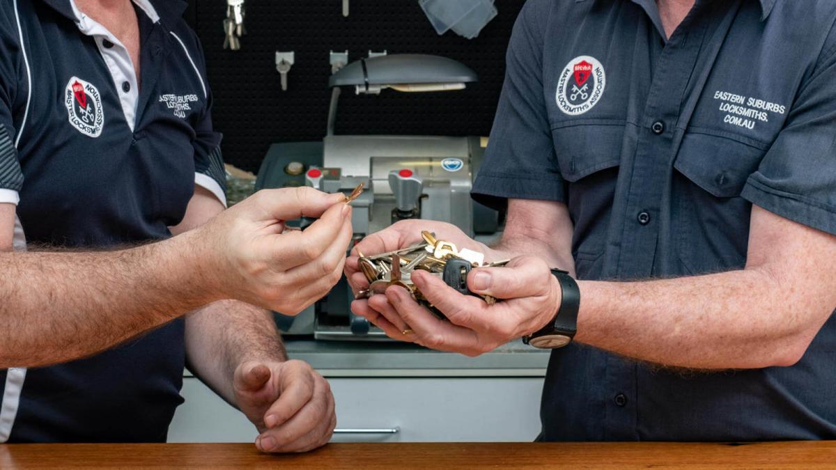 Two locksmiths handing over a set of keys beside a service vehicle