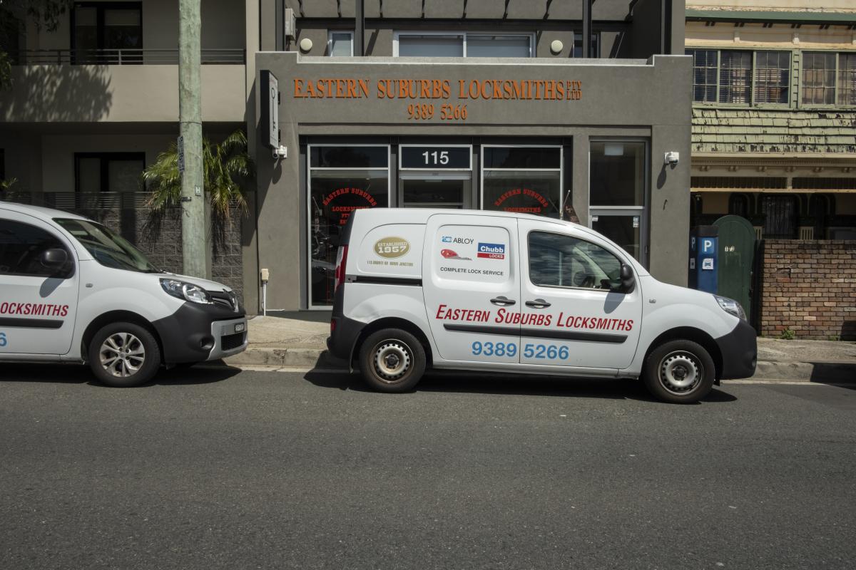 Mobile locksmith van parked outside a locksmith shop on an urban street
