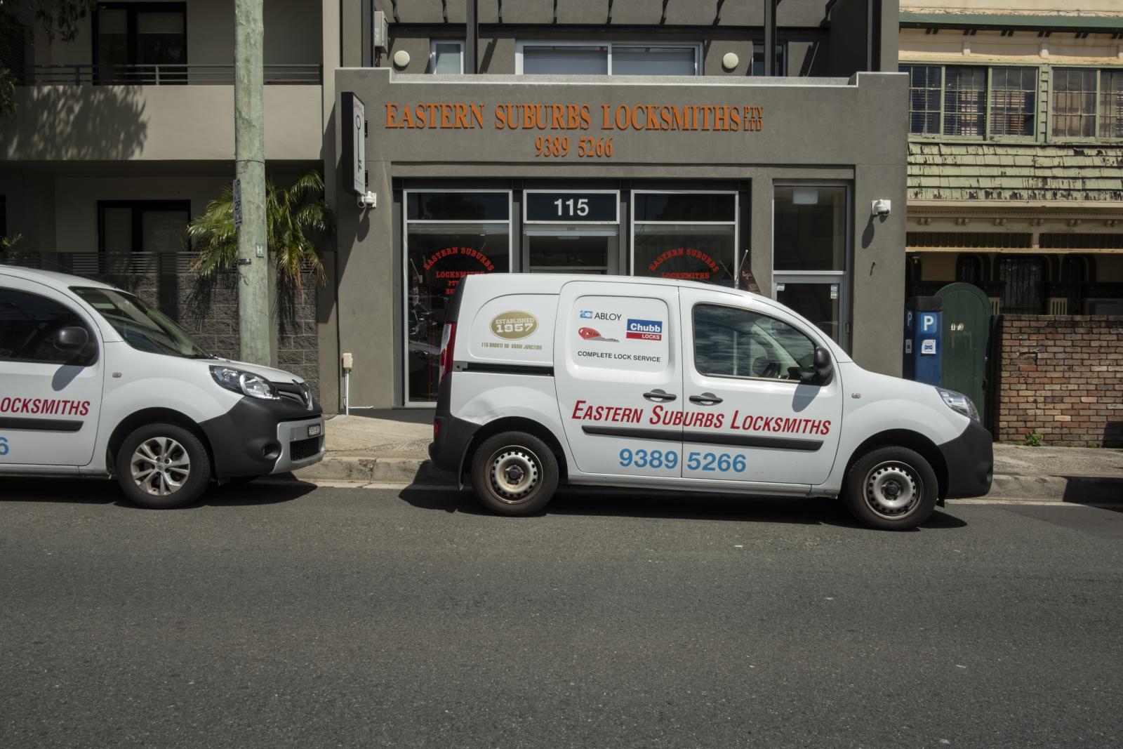 Mobile locksmith van parked outside a locksmith shop on an urban street