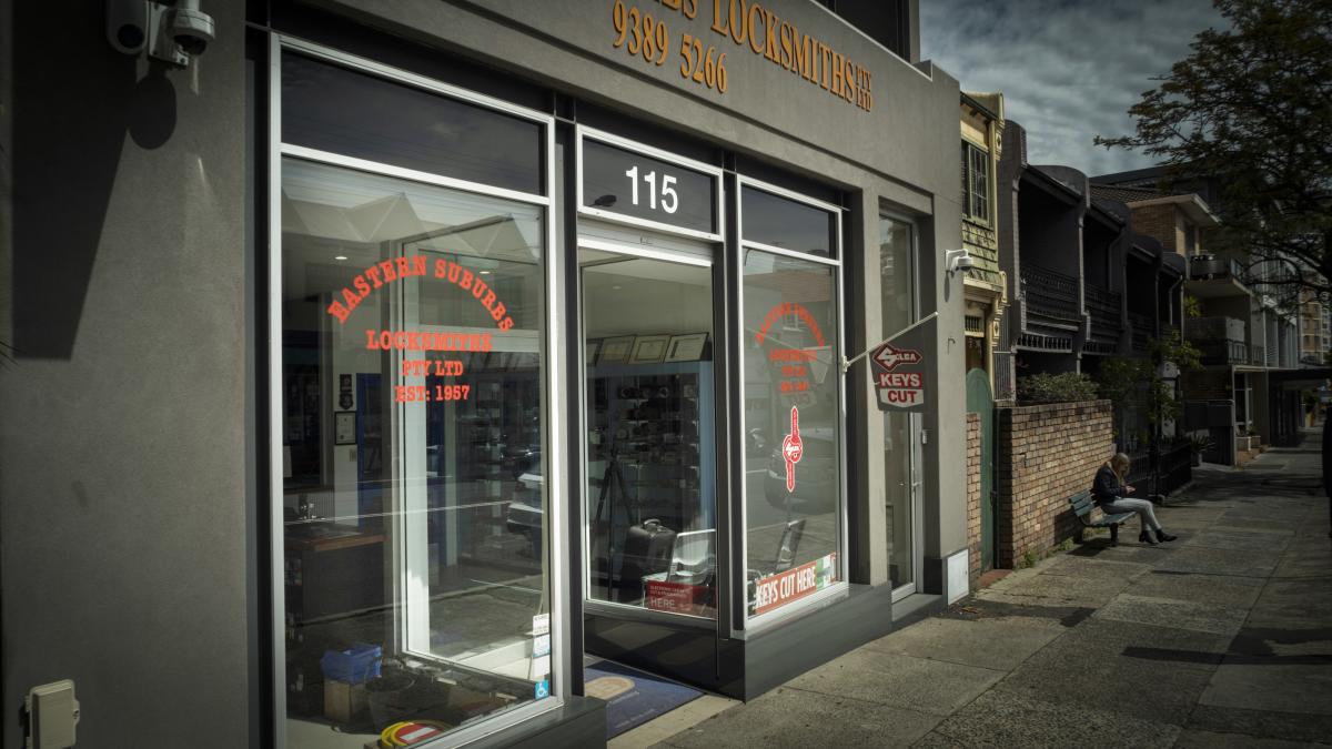 Street view of a locksmith shopfront with glass windows and security signage