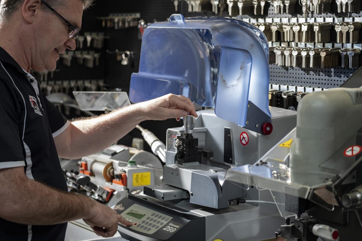 Locksmith cutting a key on a key cutting machine in a workshop