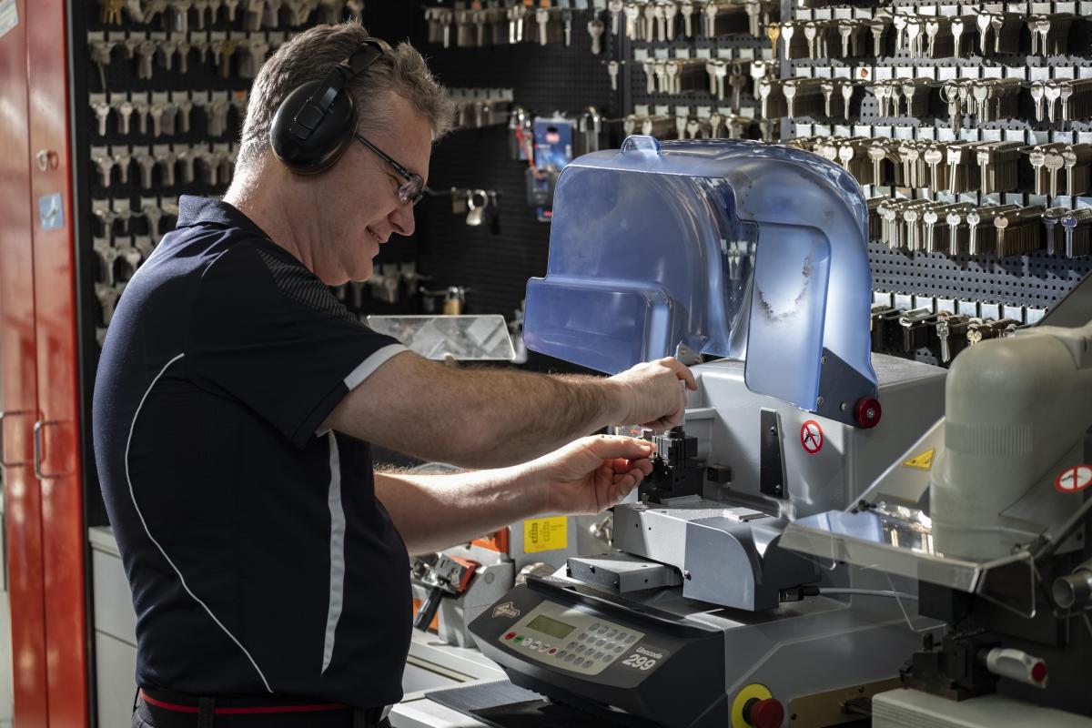 Locksmith cutting a key on a machine inside a key cutting shop