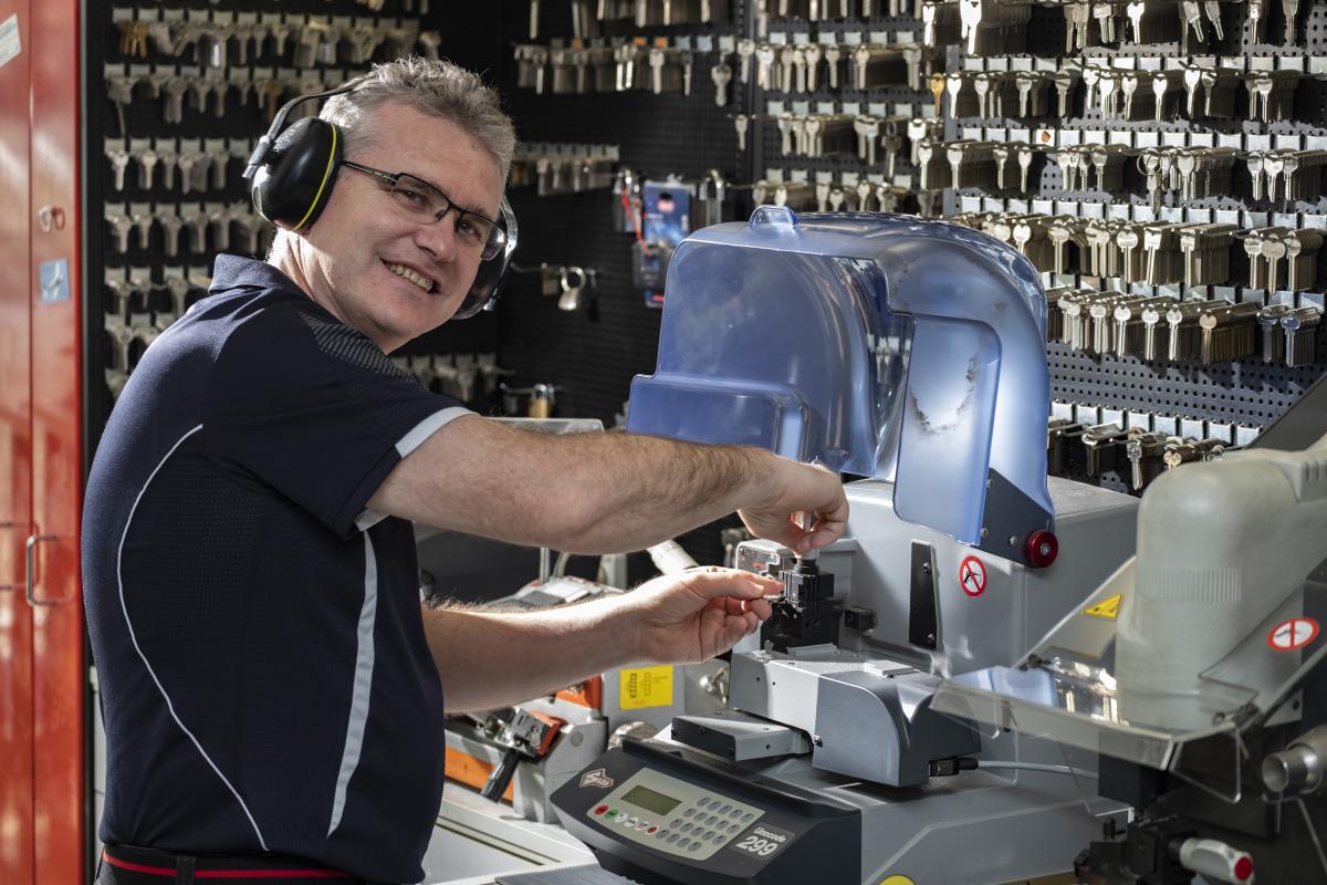 Locksmith cutting a key on a key cutting machine in a workshop