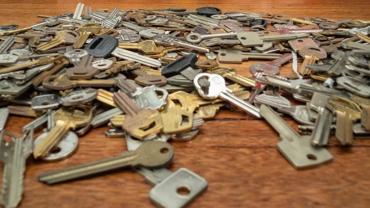 Large collection of assorted keys spread across a wooden surface