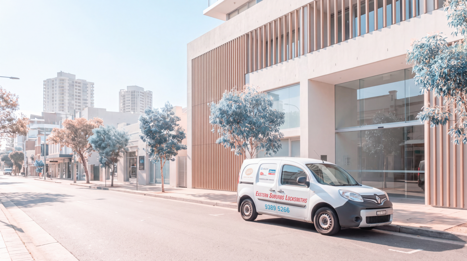 Mobile locksmith van parked outside a modern commercial building on a quiet city street