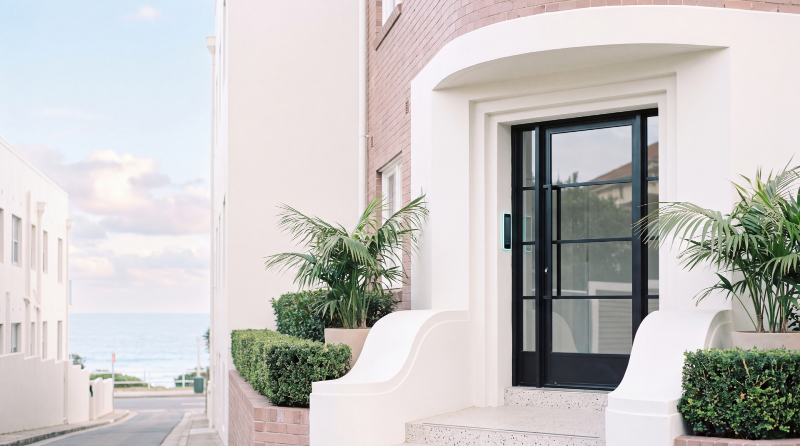 Secure black-framed entry door on a coastal residential property with landscaped entrance