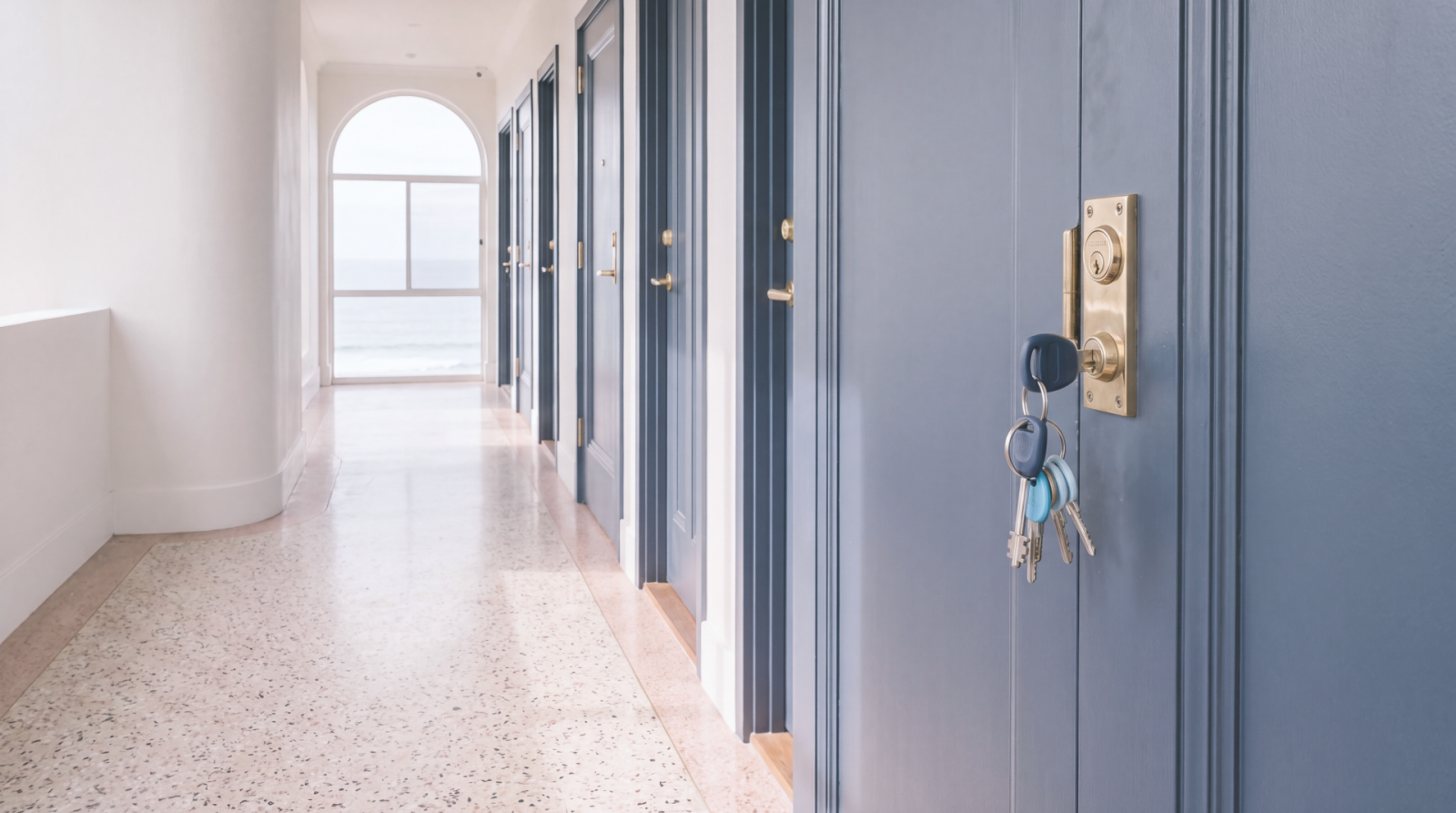 Key left in the lock of a blue apartment door in a shared residential corridor