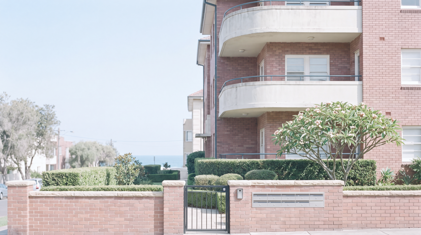 Brick apartment building with gated entrance and landscaped front garden