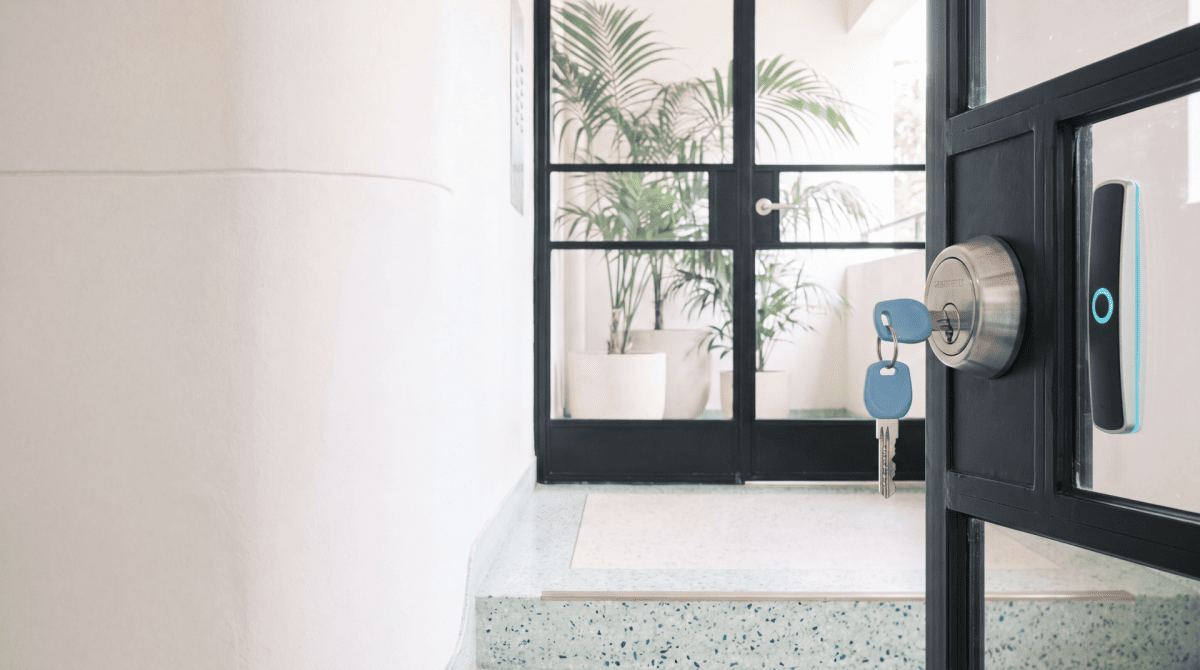 Modern electronic door lock on a glass entry door in a bright residential hallway